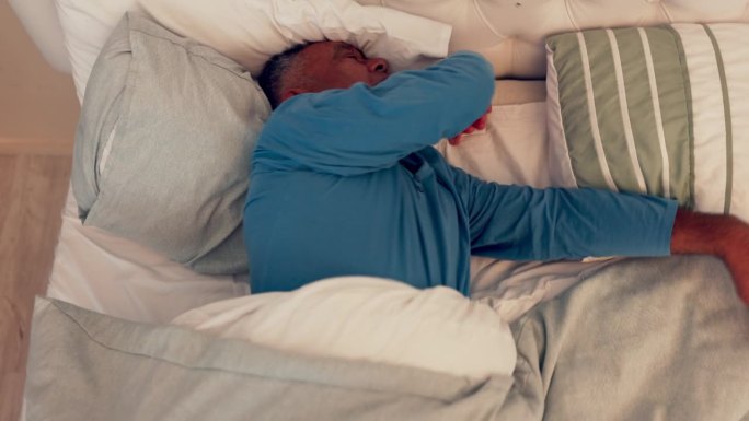 睡眠问题，老人和失眠在床上在家里的压力和恶梦。房子、顶楼和成熟的男性因疲劳而感到沮丧，睡姿不舒服而感