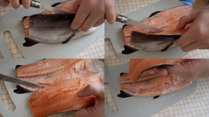 男性用刀切鳟鱼。厨师在餐桌上用刀从鱼骨架上切下一片鱼片。厨师在厨房准备鱼。厨师正在切菜板上工作。