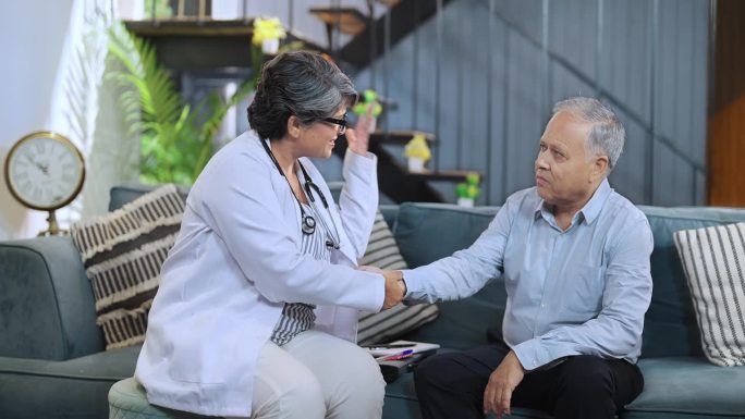 印度有爱心的女药剂师医生在医疗保健咨询时拜访老病人，坐在椅子上在书上写药方，解释帮助开药