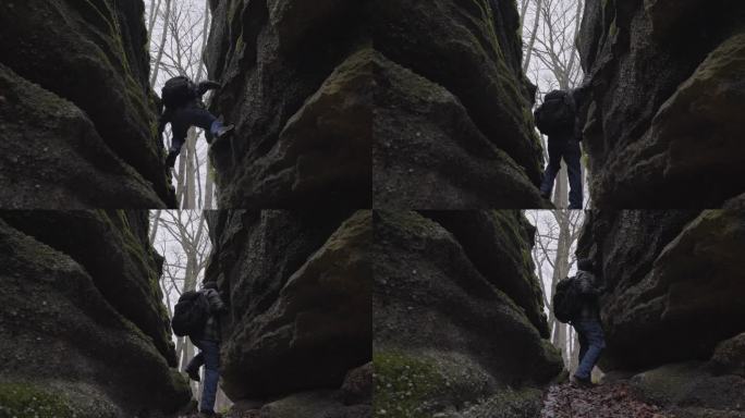 徒步旅行者通过压住岩石壁，把自己降到覆盖着树叶的森林地面上，爬下岩石裂缝