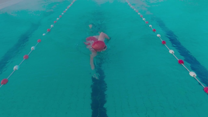 SLO - MO高角度跟踪拍摄的决心运动女子在游泳池自由泳在度假村