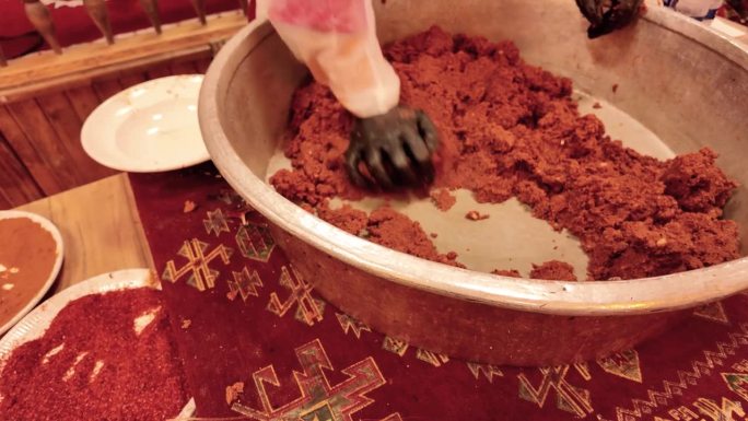 在传统的西拉之夜，一名妇女正在用慢动作在铜盘里揉制传统的土耳其生肉丸。