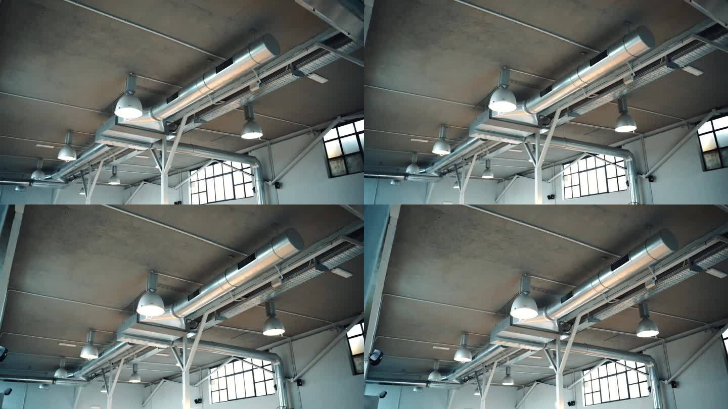 大型工作空间的投影通风系统，悬挂灯具和大窗户，金属管道冷却空间，使空气循环