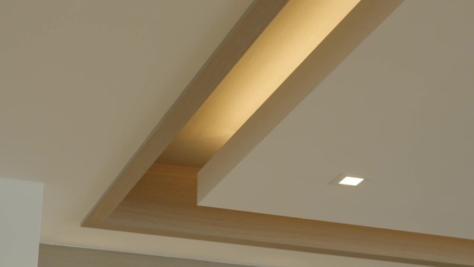 复杂形状的多层白色吊顶的一角，方形卤素点灯和干墙结构装饰了改造后公寓的空房间