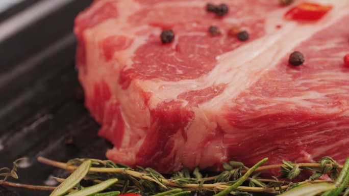 新鲜的大理石牛肉与胡椒，盐和迷迭香特写特写。准备烤多汁的牛排。优质有机生和牛肉