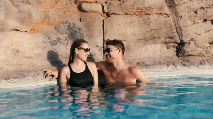 微笑的情侣一起在温泉泳池放松。浪漫的度假