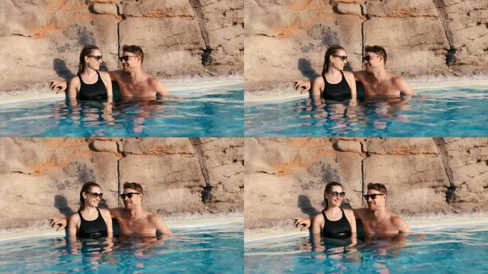 微笑的情侣一起在温泉泳池放松。浪漫的度假