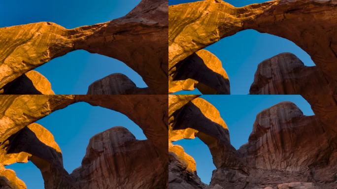 犹他州拱门国家公园的双拱门。清晨日出，阳光洒在著名的岩层上。蓝天风景美国西部狂野西部景观。