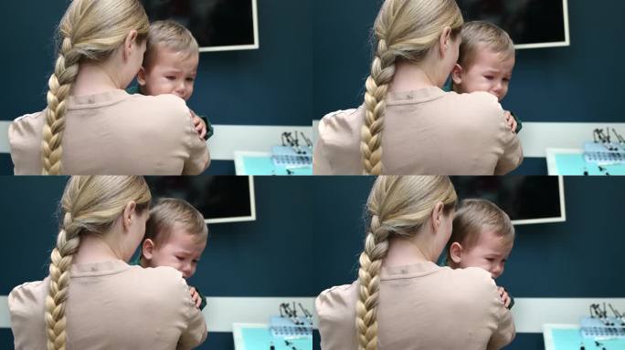 看牙医时，母亲在安慰哭闹的儿子。