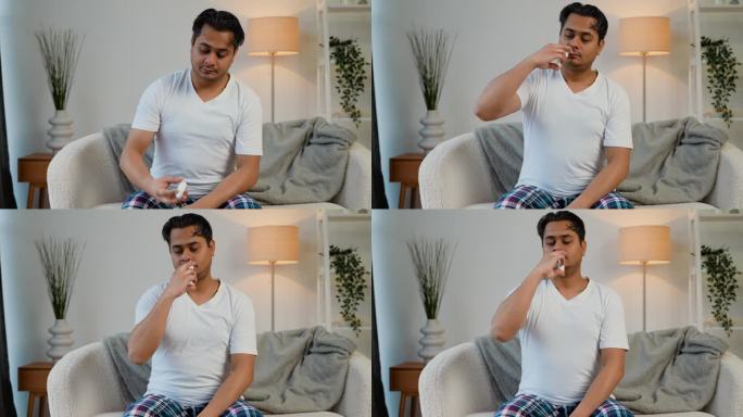 印度男子坐在沙发上喷鼻喷雾剂。病毒性疾病的概念