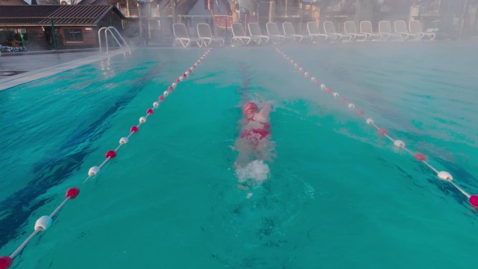 户外度假胜地雾蒙蒙的游泳池里，坚定的女子练习自由泳的镜头