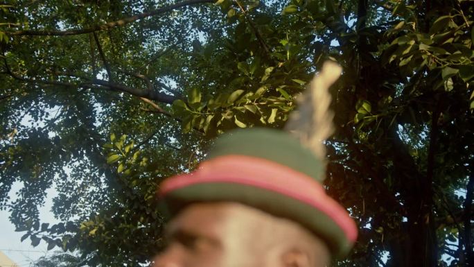 非洲乌干达，日落时分，卡拉莫琼部落的战士在丛林中戴着羽毛帽。倾斜，机架对焦