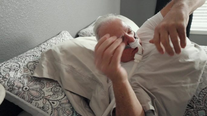 成年男子在被诊断为睡眠呼吸暂停后，在CPAP(持续气道正压通气)机下挣扎和翻滚