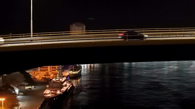 弯曲的朱莉安娜桥勾勒出夜晚汽车飞驰而过的Handelskade，鸟瞰图