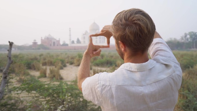 在印度旅行的年轻人用手和手指勾勒出泰姬陵的轮廓