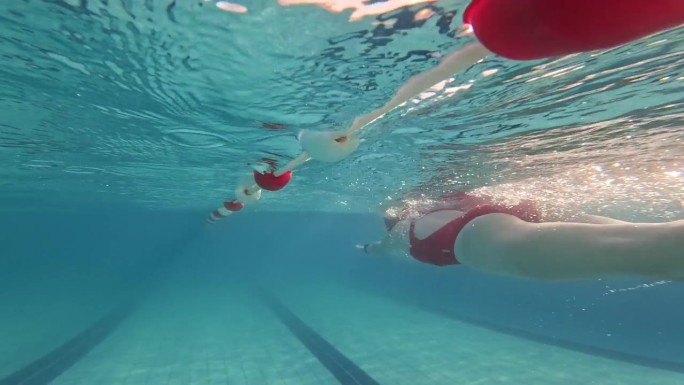 白天在度假胜地绿松石泳池游泳的坚定运动女子的水下跟踪镜头