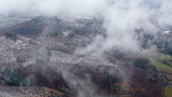 积雪覆盖着山脉，从上面看，云层散开，露出冬日的风景，无人机拍摄了这张照片。
