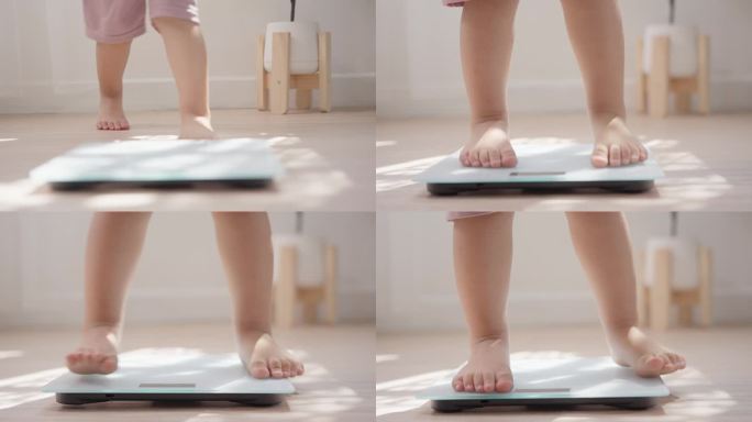 小婴儿赤脚站在家里的木地板上称体重。儿童体重控制概念。