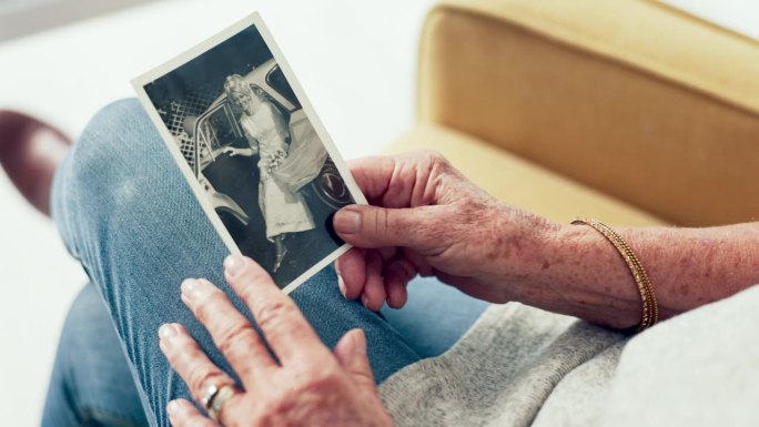 老人在疗养院里回想过去的手，照片和记忆。历史，复古和退休与一个老人拿着照片近距离回忆生活
