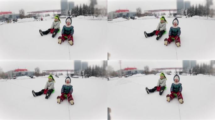 溜冰鞋。两个女孩愉快地在白雪覆盖的城市里骑着迷你雪橇打滚。用嘴捕捉雪花。脱碳，地球大气中的不平衡。慢