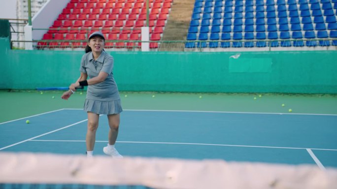 一对亚洲老年夫妇一起打网球混双比赛，最终他们成为冠军。美丽而强壮的50多岁的女人，刚刚和她的伴侣，一