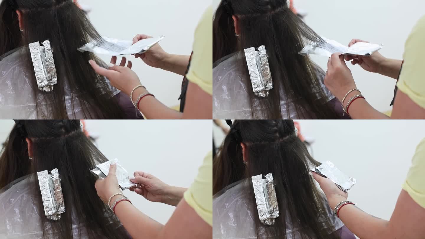 理发师用箔纸把一个女人染过的头发包起来。