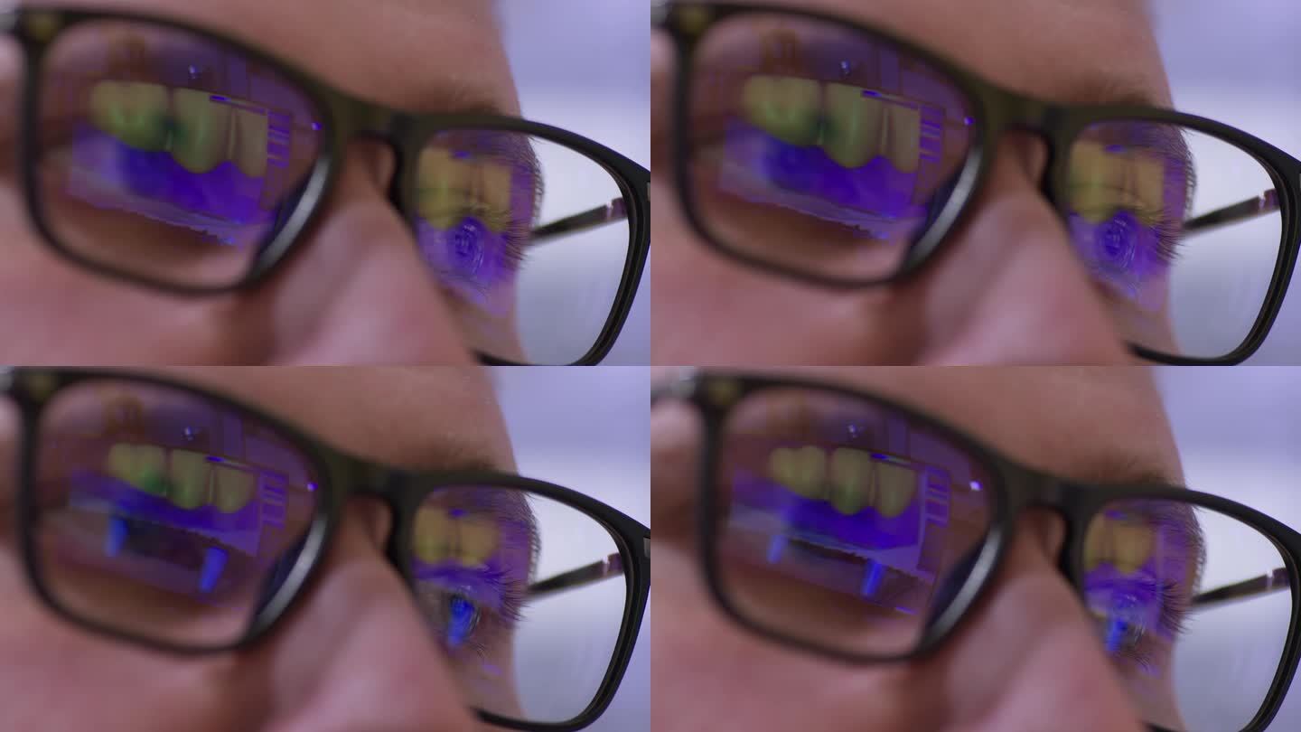 用人工下巴模拟程序的显示器在男子眼镜上的反射。