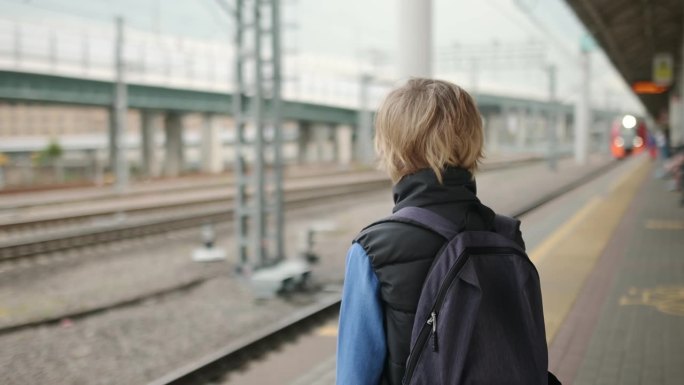 一个可爱的十几岁的男孩在火车站站台或地铁站等火车。大都市交通系统。