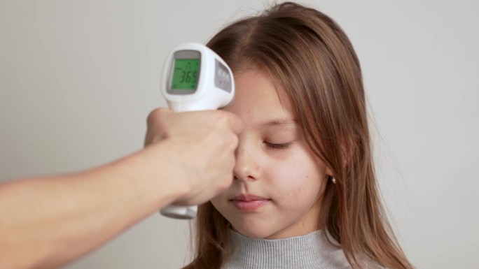 用红外线额头温度计用手检查孩子的体温