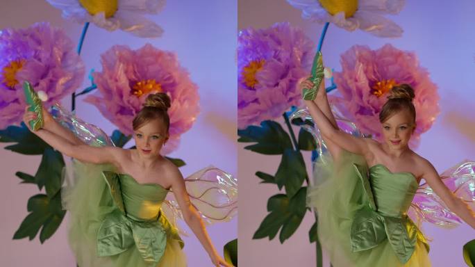 小孩子穿着绿色的仙女裙，带着半透明的翅膀，在巨大的花朵中摆姿势。