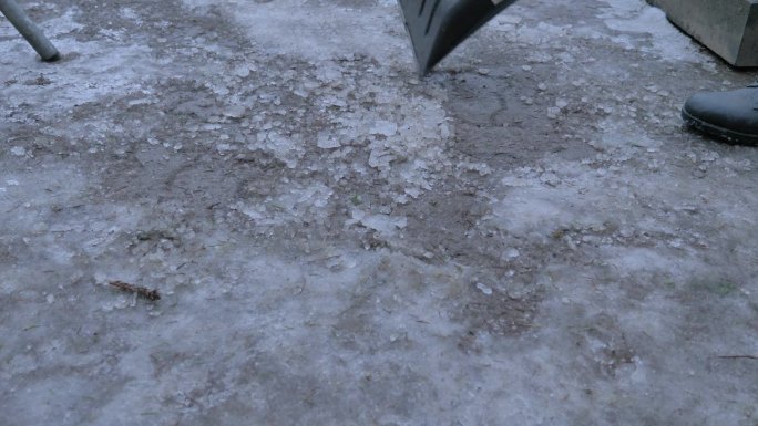 街道清洁工用铁锹清除道路上的冰雪，使行走安全