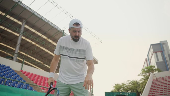 一名白人高级网球运动员，身穿白色运动服，戴着遮阳帽，在网球场上练习正反手击球。老年友谊和积极的老年生