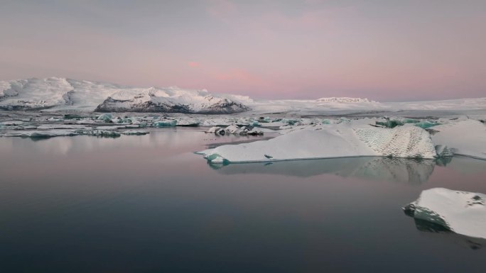 粉红色的日出天空和冰山反映在Jokulsarlon冰湖上。冰岛南部的瓦特纳冰川国家公园。无人驾驶飞机