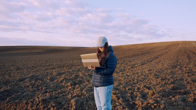 SLO MO年轻农艺师在分析农村耕地时使用笔记本电脑