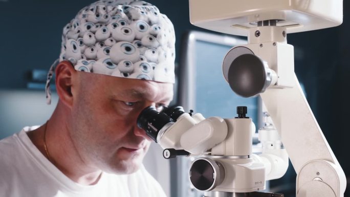 眼科医生坐在显微镜前做手术。进行高精度手术的男医生。飞激光白内障手术。