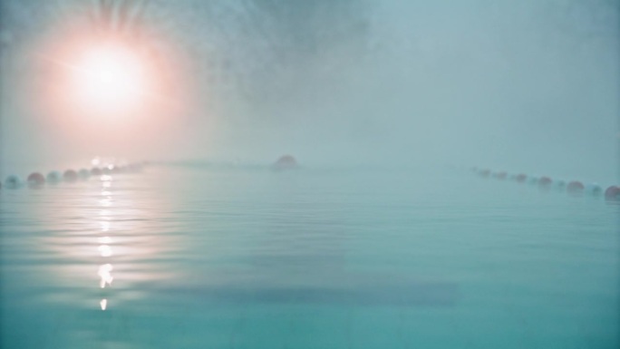 在黎明的大雾天气中，坚定的年轻女子在度假村游泳池游泳的锁定镜头