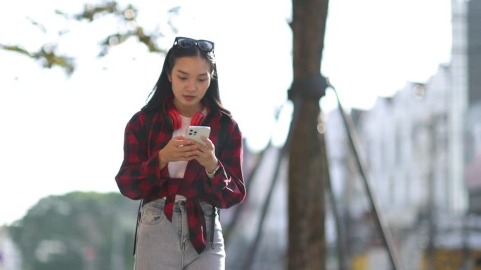走在人行道上用手机的年轻女子。