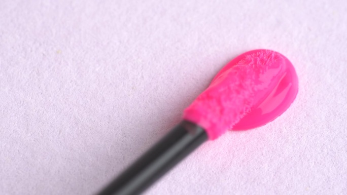 霓虹粉色唇彩。粉色口红，唇彩质地，微距。化妆品在时髦的粉红色涂抹涂抹样品样品。