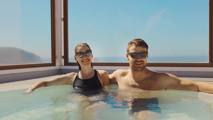 一对夫妇在阳光明媚的日子里在屋顶热水浴缸里放松。暑假，度假旅游