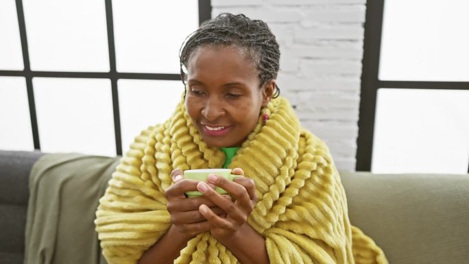 穿着黄袍子的非裔美国妇女在家里喝咖啡