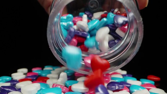 从罐子里倒出来的是五颜六色的心，用来装饰朝着镜头移动的糖果。多莉滑块，近一点。