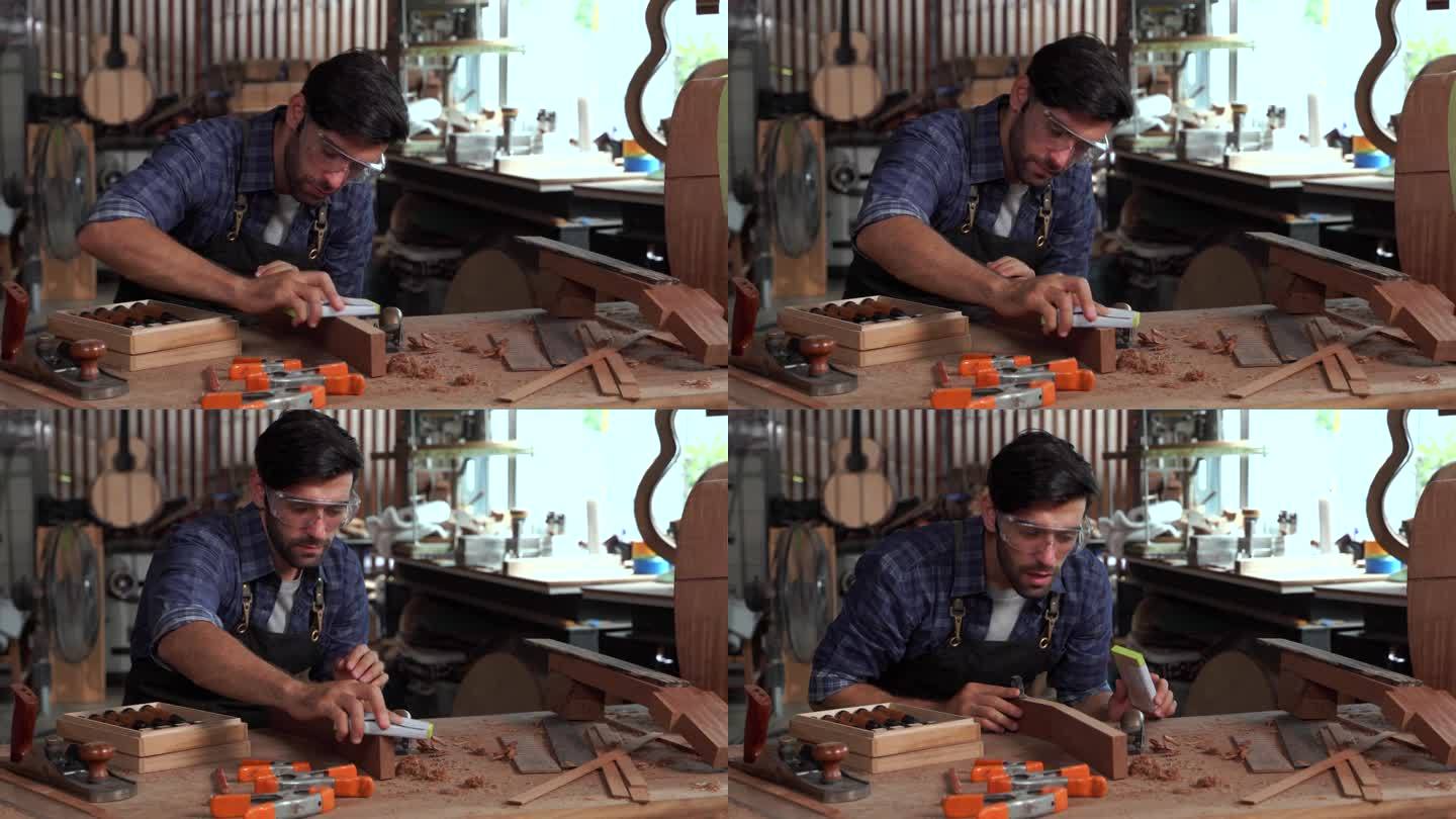 琵琶及原声乐器制作车间。成年工匠用木头和凿子制作一把古典吉他。