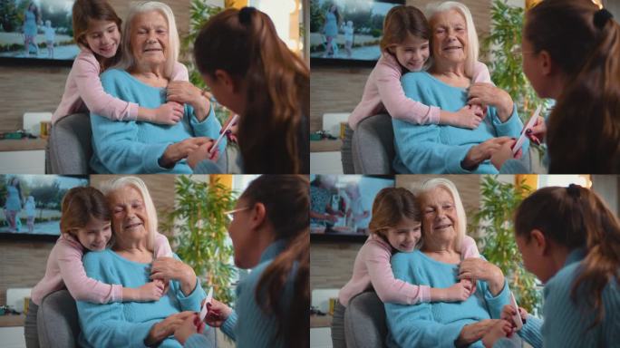 美丽和时尚的概念，一个80年代的老妇人在家里修指甲，她的成年女儿在她的孙女拥抱她的时候修指甲