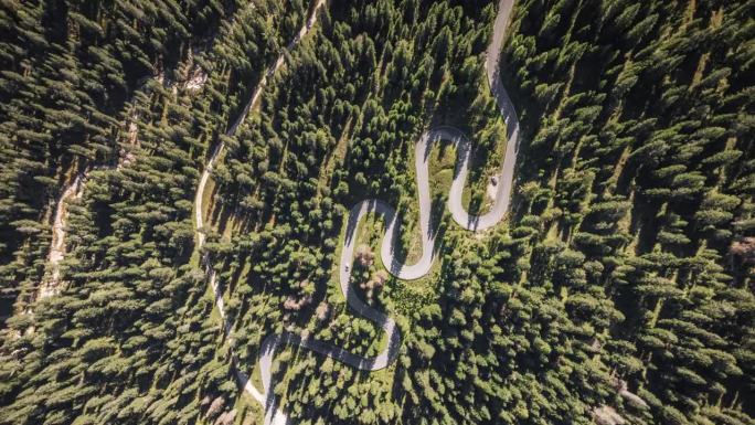 在意大利多洛米蒂山脉最著名的多洛米蒂山脉之一的松树环绕的蜿蜒曲折的道路上行驶的汽车的4K鸟瞰图