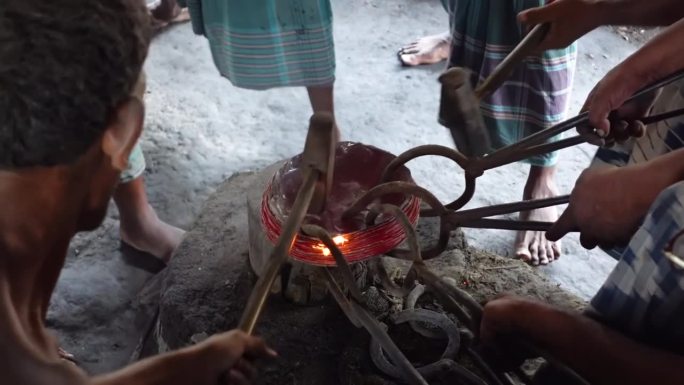 在一个农村工厂里，人们用大锤子敲打热铜锭来制造家用电器。