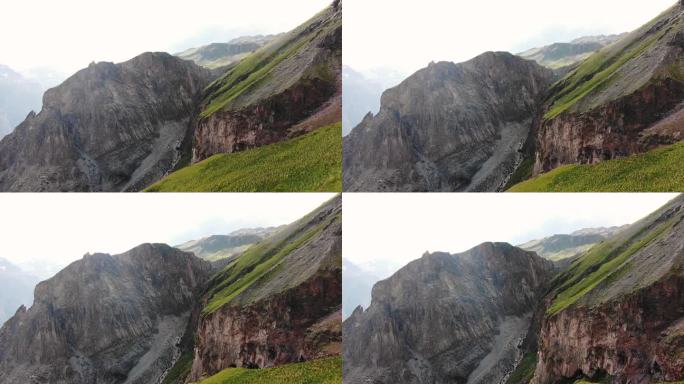 崎岖的山崖面与片片绿色植被形成鲜明对比，展示了高山景观的多种纹理和颜色。