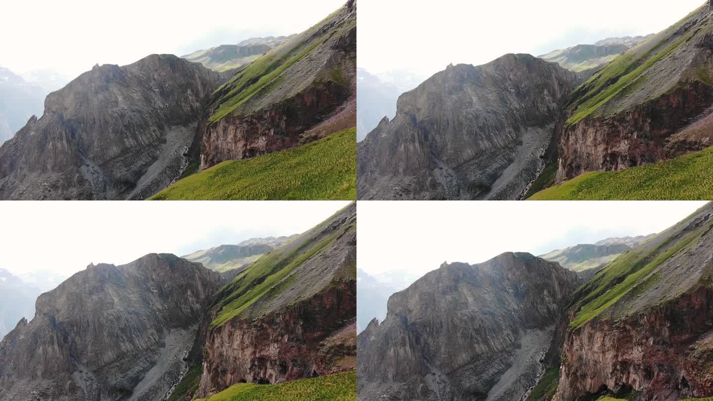 崎岖的山崖面与片片绿色植被形成鲜明对比，展示了高山景观的多种纹理和颜色。