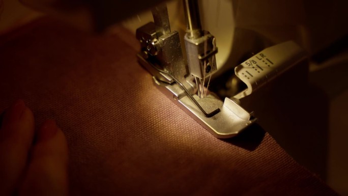 包边缝纫机在织物上缝制下摆。用包边缝纫机进行精密折边，展示了详细的缝合。
