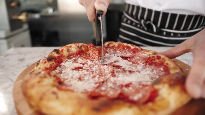 食物，烹饪，意大利菜，人和烹饪概念-厨师手添加磨碎的奶酪比萨在比萨店