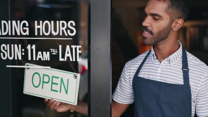 在小店铺、咖啡厅或餐厅的窗口开、签、开、开。店铺、通知和业主的手在早上更换营业时间的标牌、公告板或信